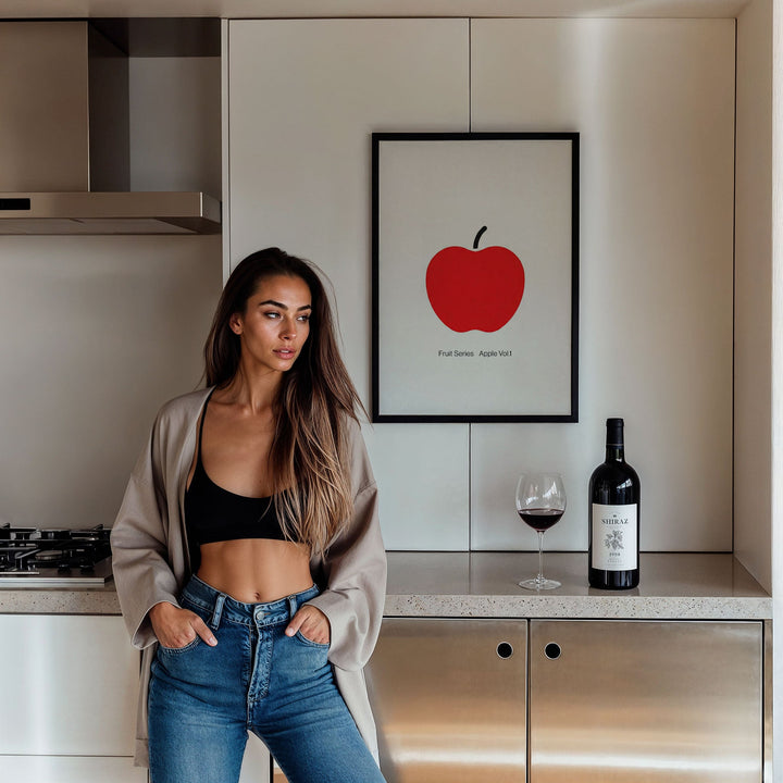Woman standing in a kitchen with a red apple poster on the wall