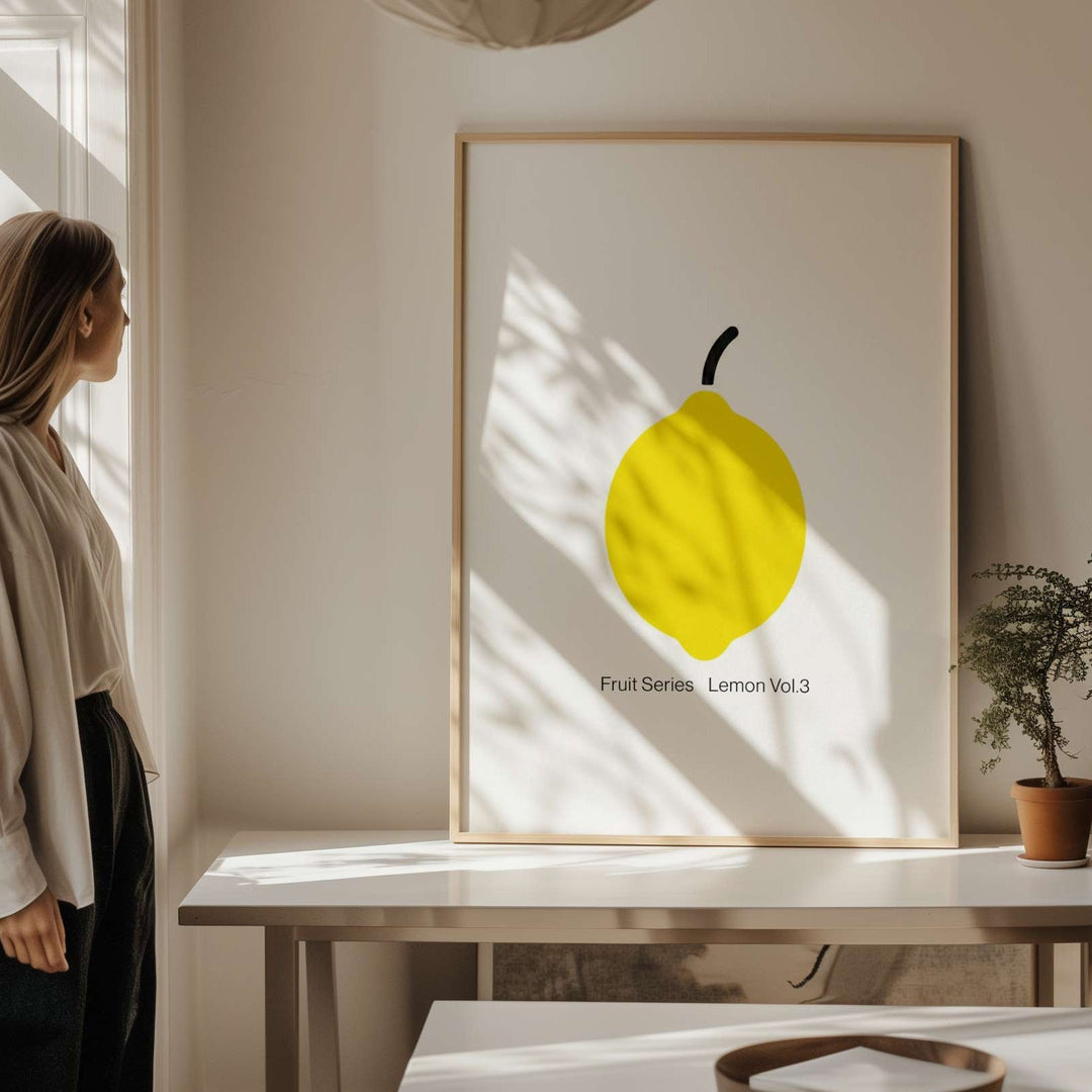Woman standing by a window in a bright room with a picture of a lemon on a table.