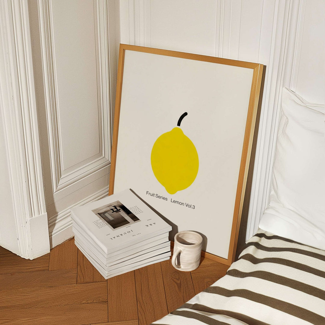 artwork of a lemon on a wall next to books and a mug.