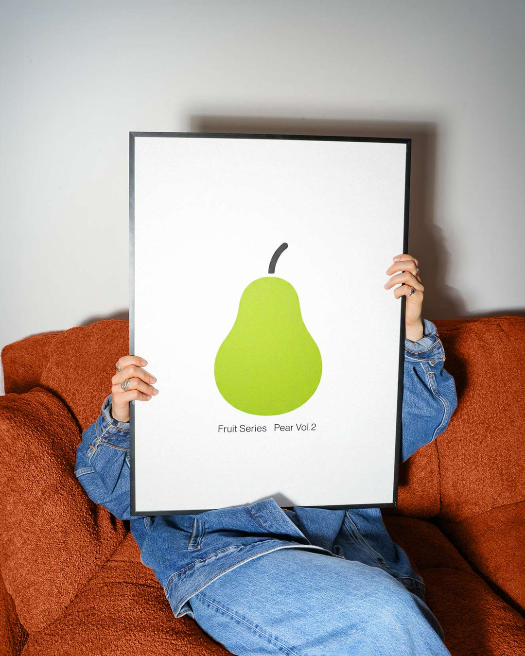 Person holding a print of a green pear against a white background