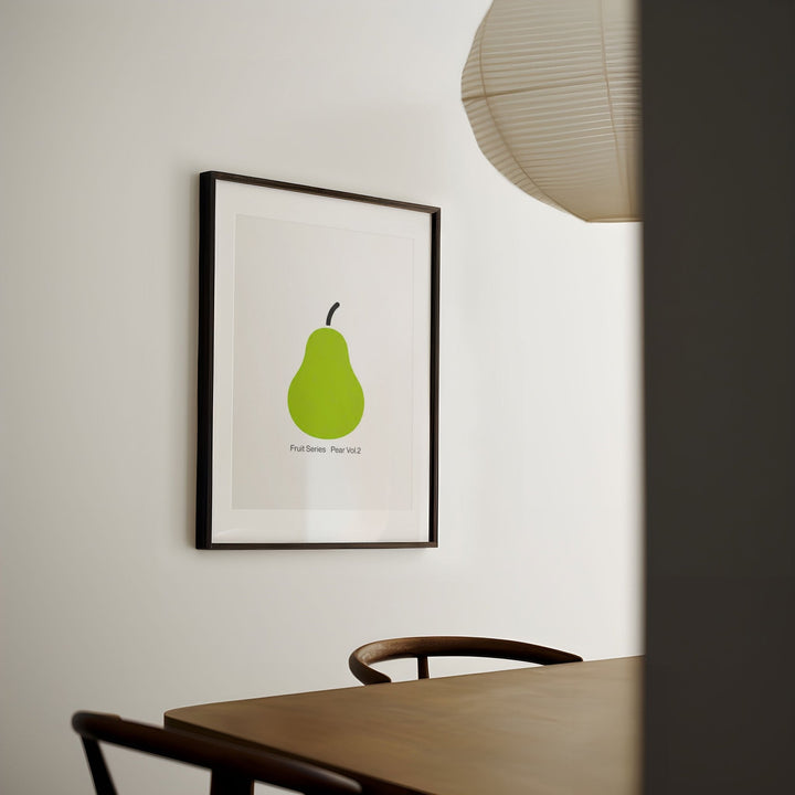 artwork of a green pear on a wall in a room with a table and chairs.