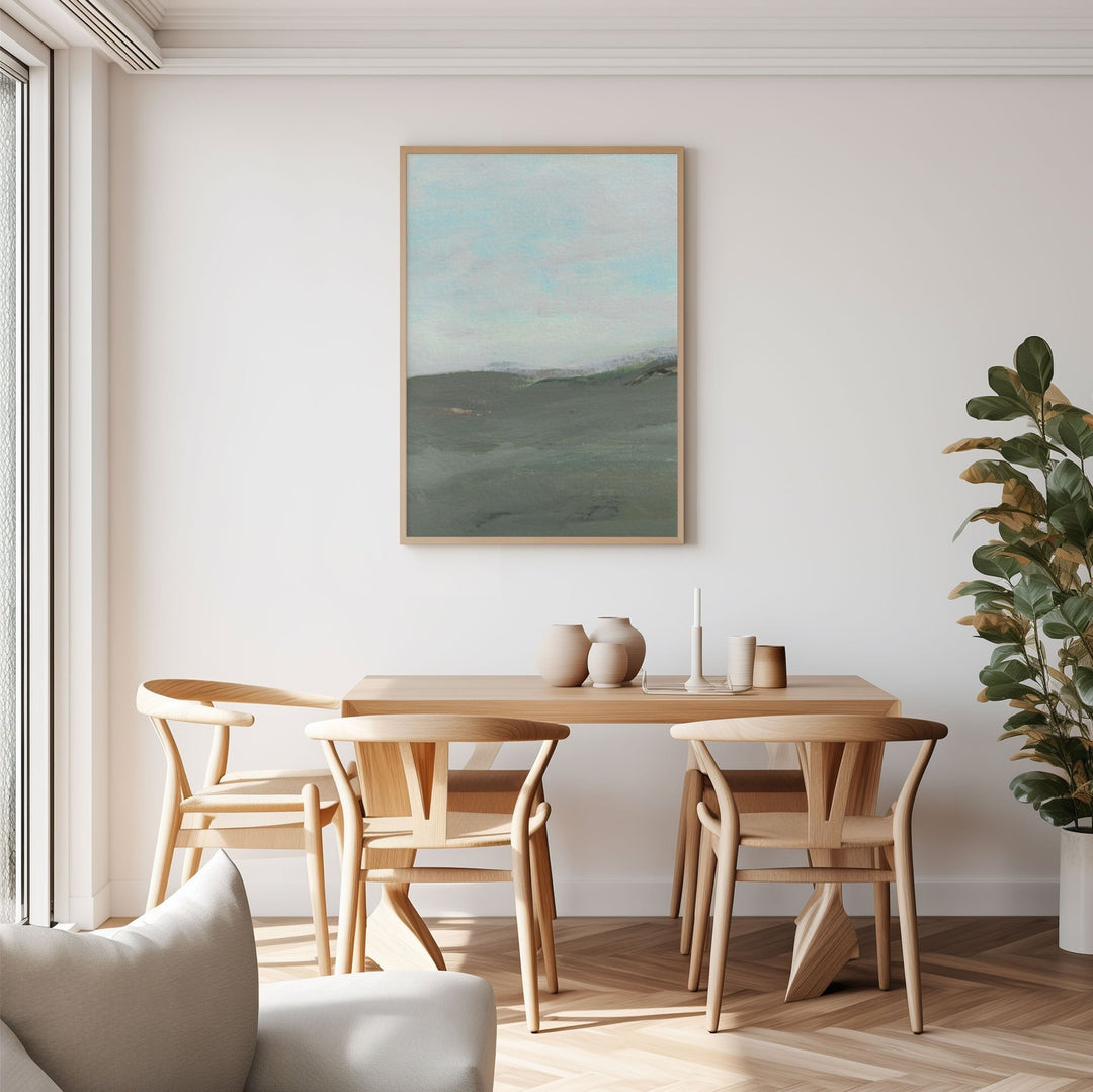 Dining room with wooden table and chairs, landscape art on the wall, and a plant.