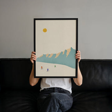 person sitting on black sofa holding an artwork of skiers
