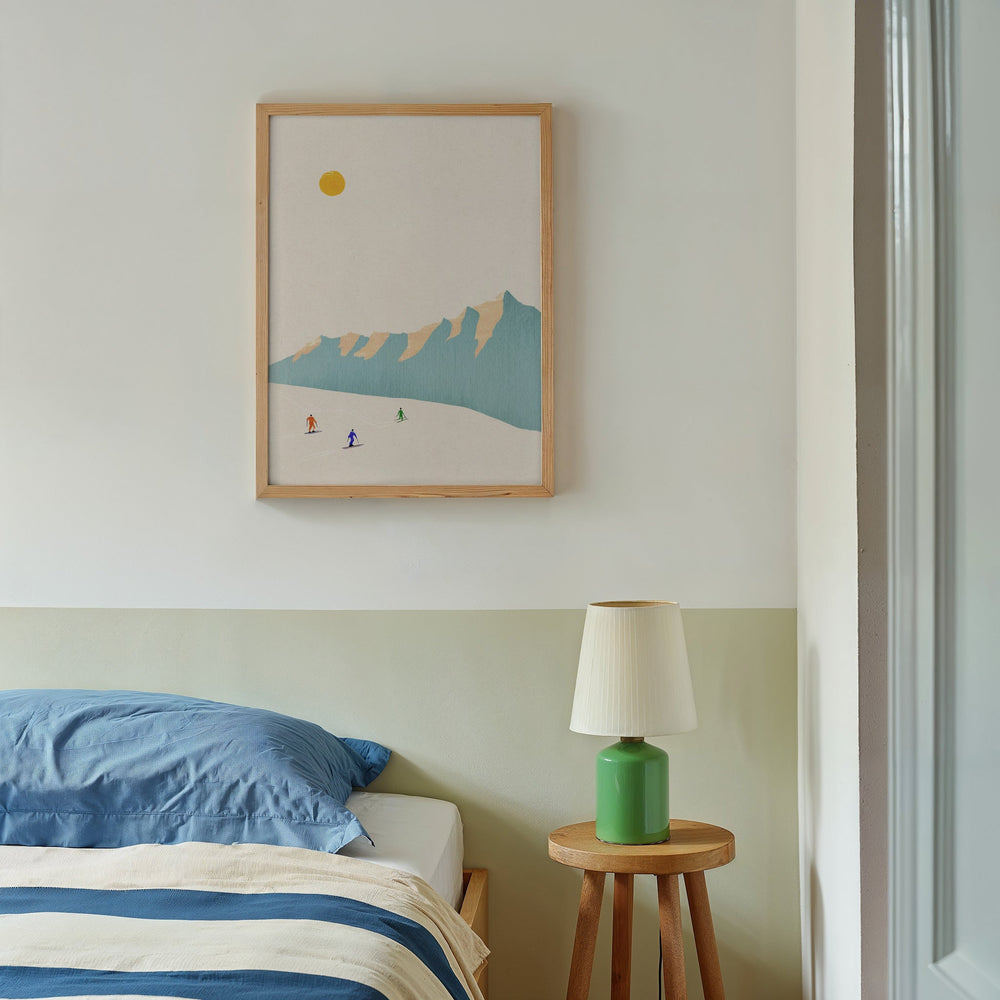 Bedroom with beside lamp and artwork of skiers hanged on white wall
