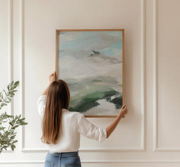 Woman hanging abstract painting on a wall