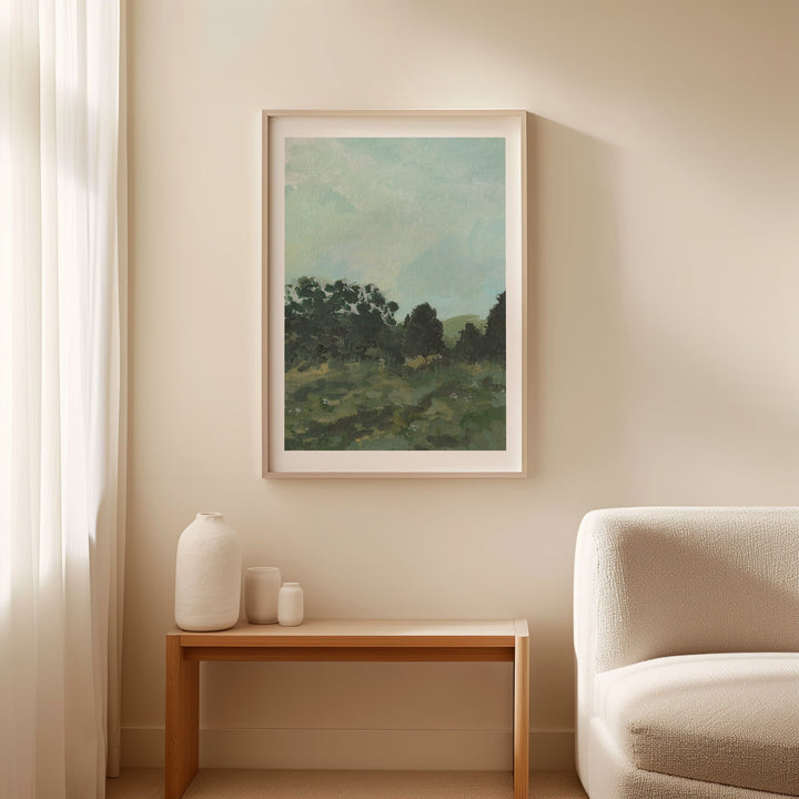 Landscape painting on a wall above a wooden side table with decorative items, next to a beige armchair.
