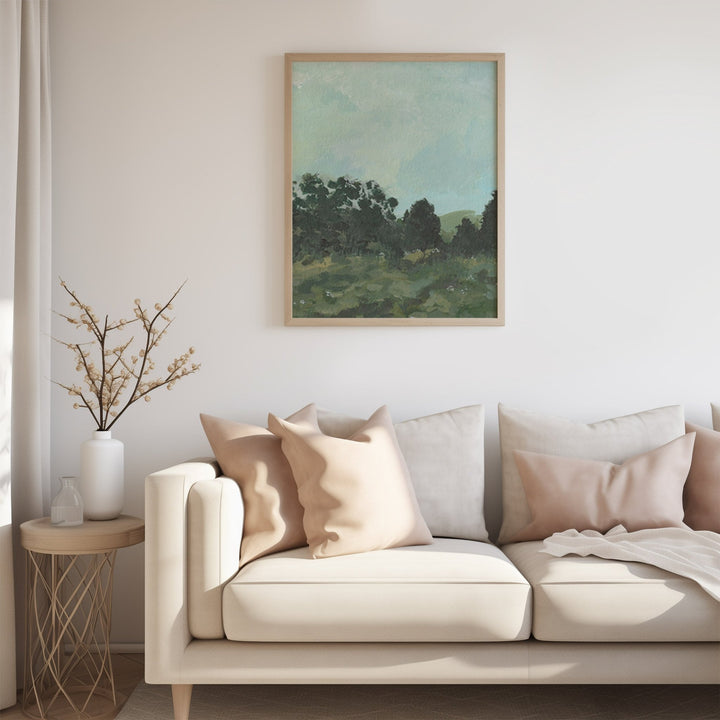 Living room with a beige sofa, decorative pillows, a small table with a vase, and a landscape painting on the wall.
