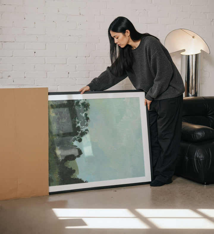 Woman holding an artwork in a living room.