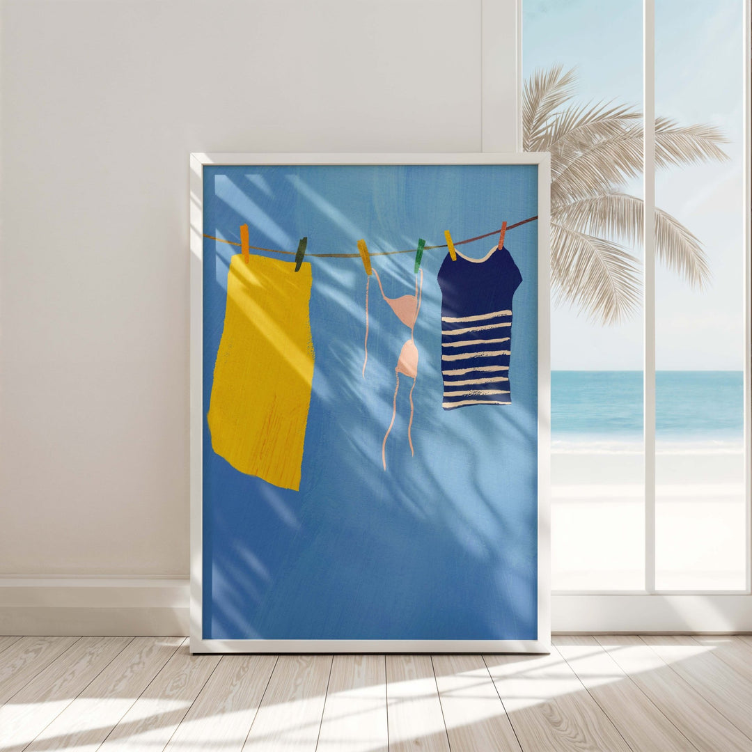 artwork of clothes on a line with a beach scene, hanging on a wall.