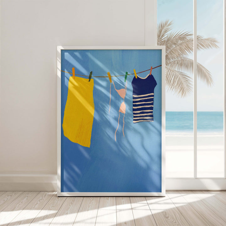 artwork of clothes on a line with a beach scene, hanging on a wall.