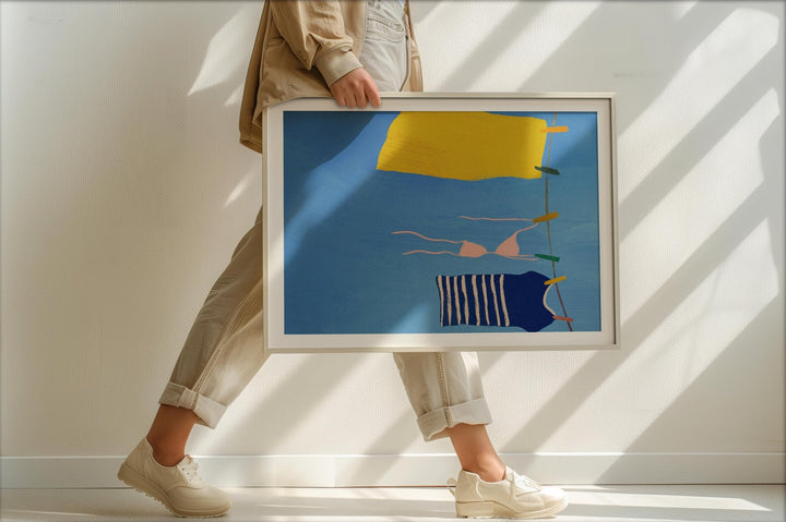 Person holding an abstract artwork with a blue sky and yellow elements.