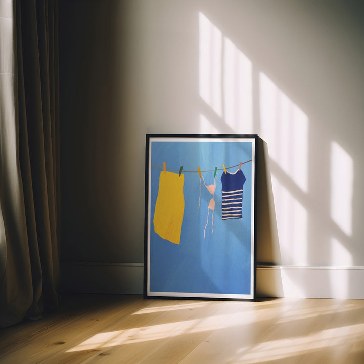 Artwork of a woman and yellow dress on a clothesline against a blue background, placed on a wooden floor with sunlight casting shadows.