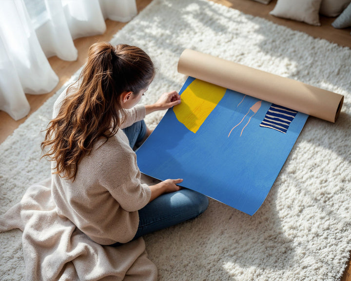 Woman sitting on a carpeted floor with a large blue sheet of paper and a roll of yellow tape.