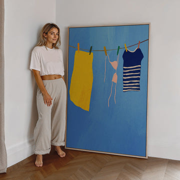Woman standing next to a large painting of clothes on a line against a white wall.