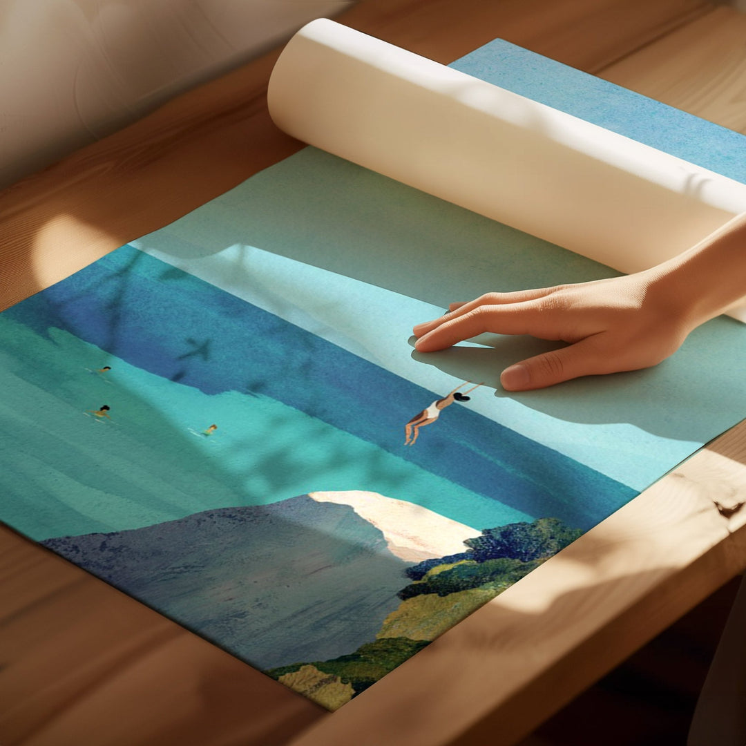 Hand rolling out a scenic rug with a mountain and beach design on a wooden floor.