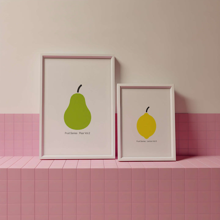 Two framed illustrations of pears on a pink tiled shelf against a pink wall.