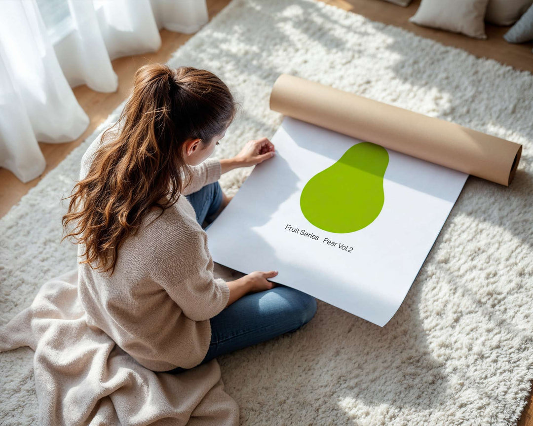 Person sitting on a carpeted floor with a large green pear print and a roll of paper.