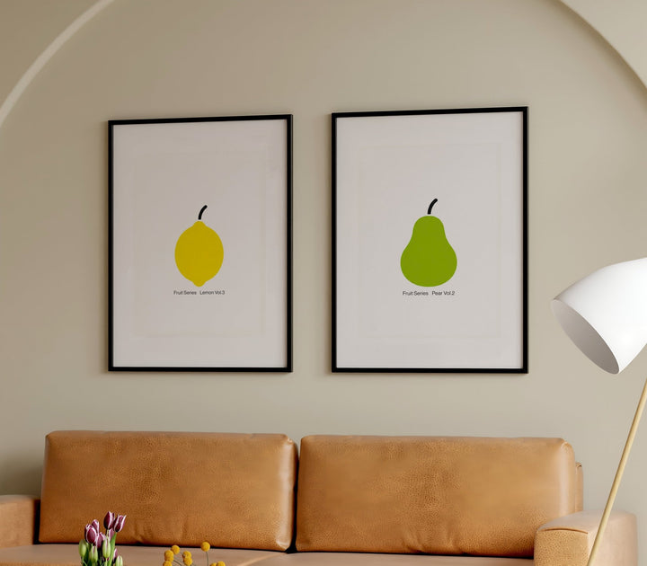 Two framed illustrations of a lemon and a pear on a wall above a sofa.