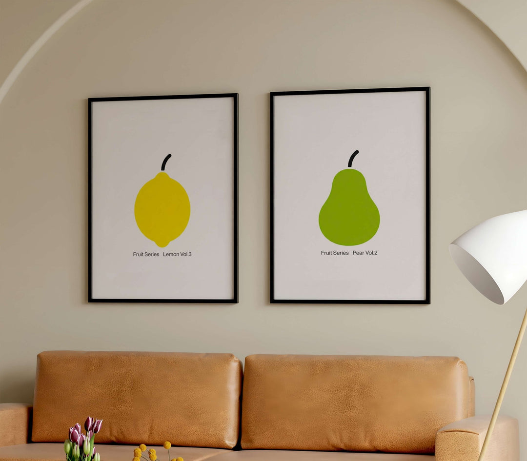 Two framed illustrations of a lemon and a pear on a wall above a brown sofa.