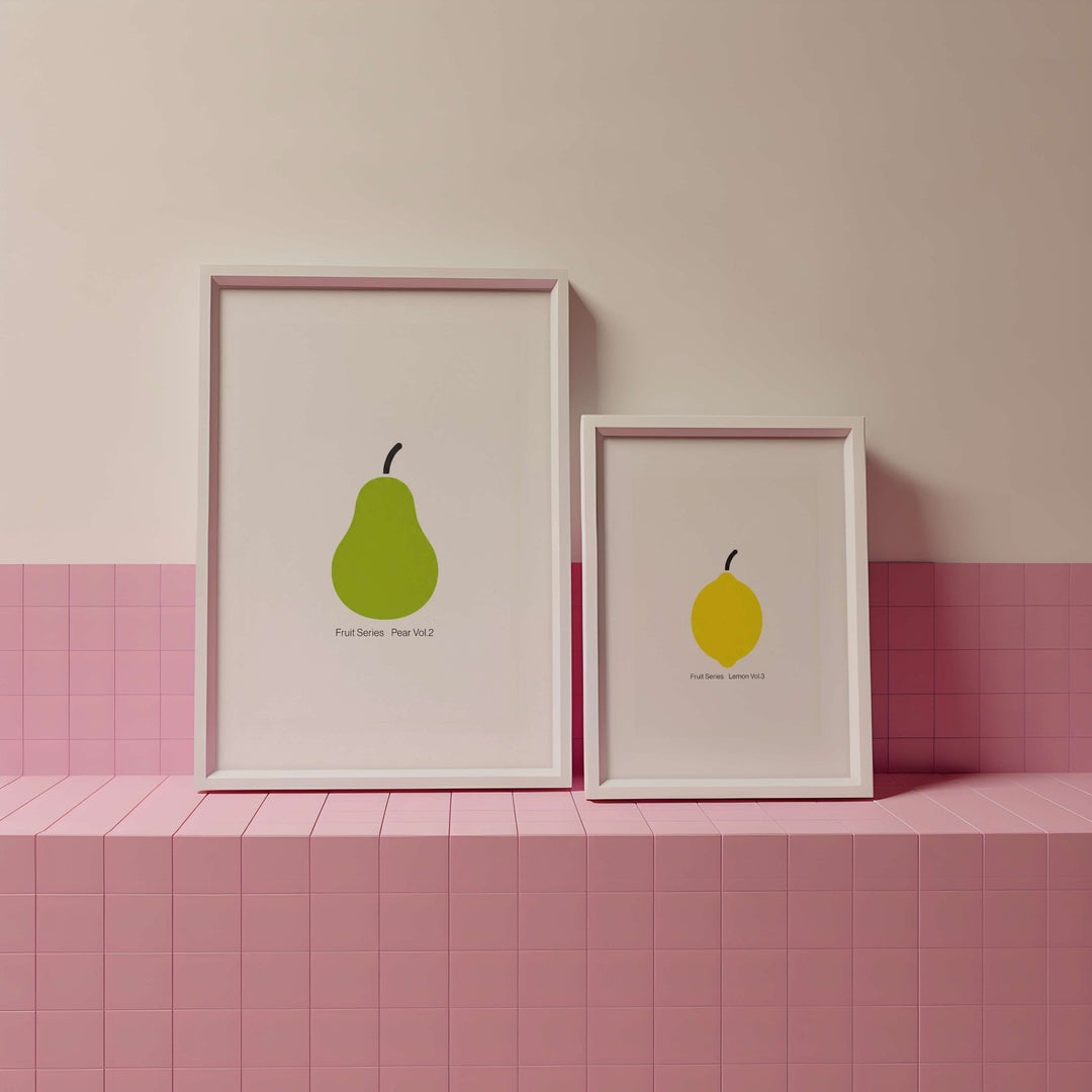 Two framed illustrations of pears on a pink tiled shelf against a pink wall.