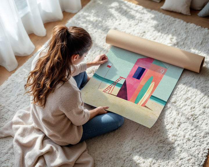 Woman unrolling a colorful abstract painting on a light-colored rug.