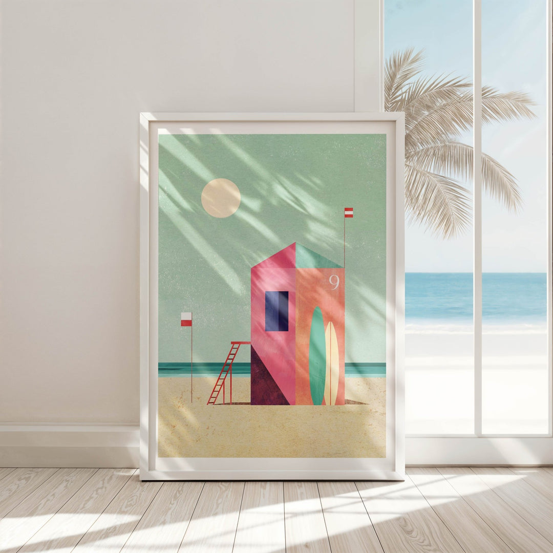 Artwork of a colorful beach scene with a hut on a green background, displayed in a room with a window showing a palm tree and ocean.