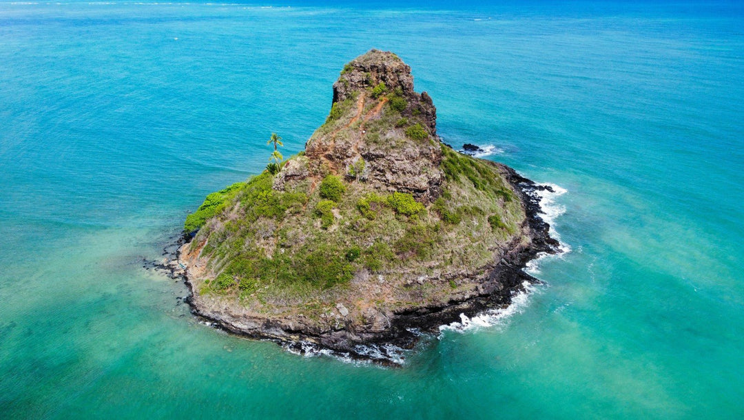 Island with a rocky outcrop in the middle of clear blue water framed