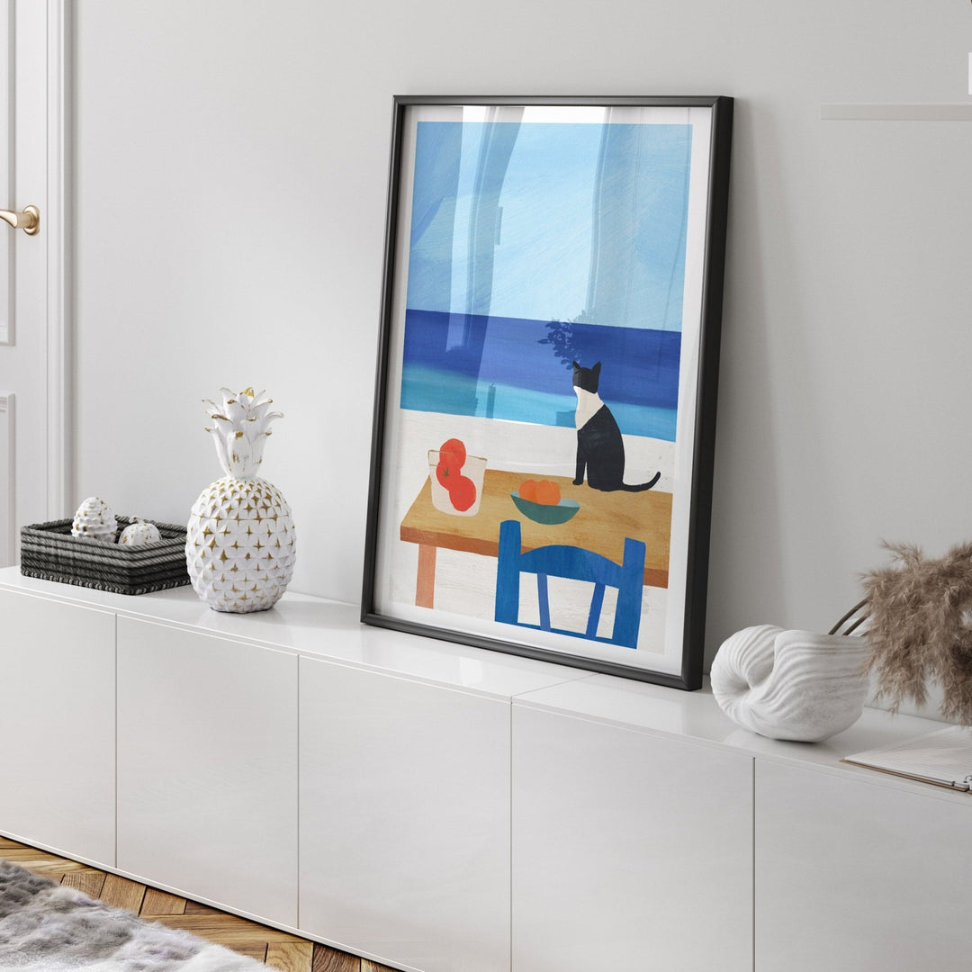 Artwork of a cat at a table on a white wall above a white cabinet.