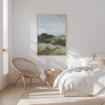 Modern bedroom with a bed, wicker chair, and landscape painting on the wall.