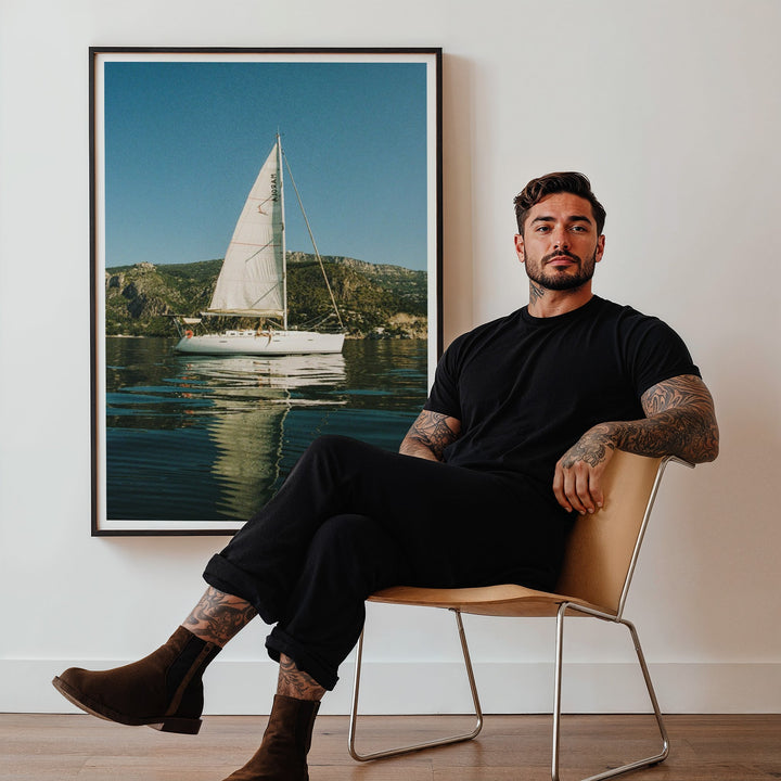 guy sitting on chair with sailboat photo on back