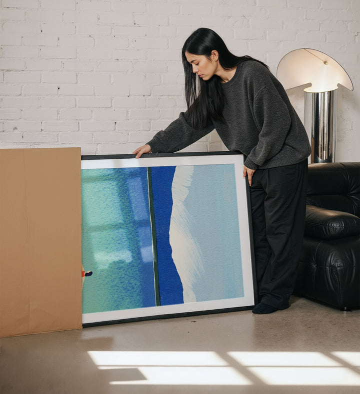 Person holding an artwork in a living room setting