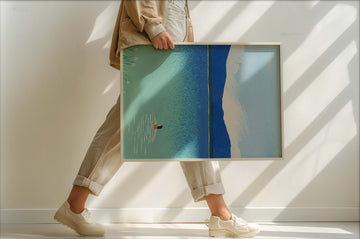 Person holding a large artwork with abstract design in a minimalistic setting