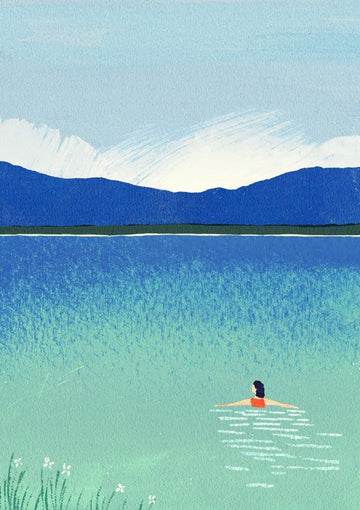 Person swimming in a lake with mountains in the background framed