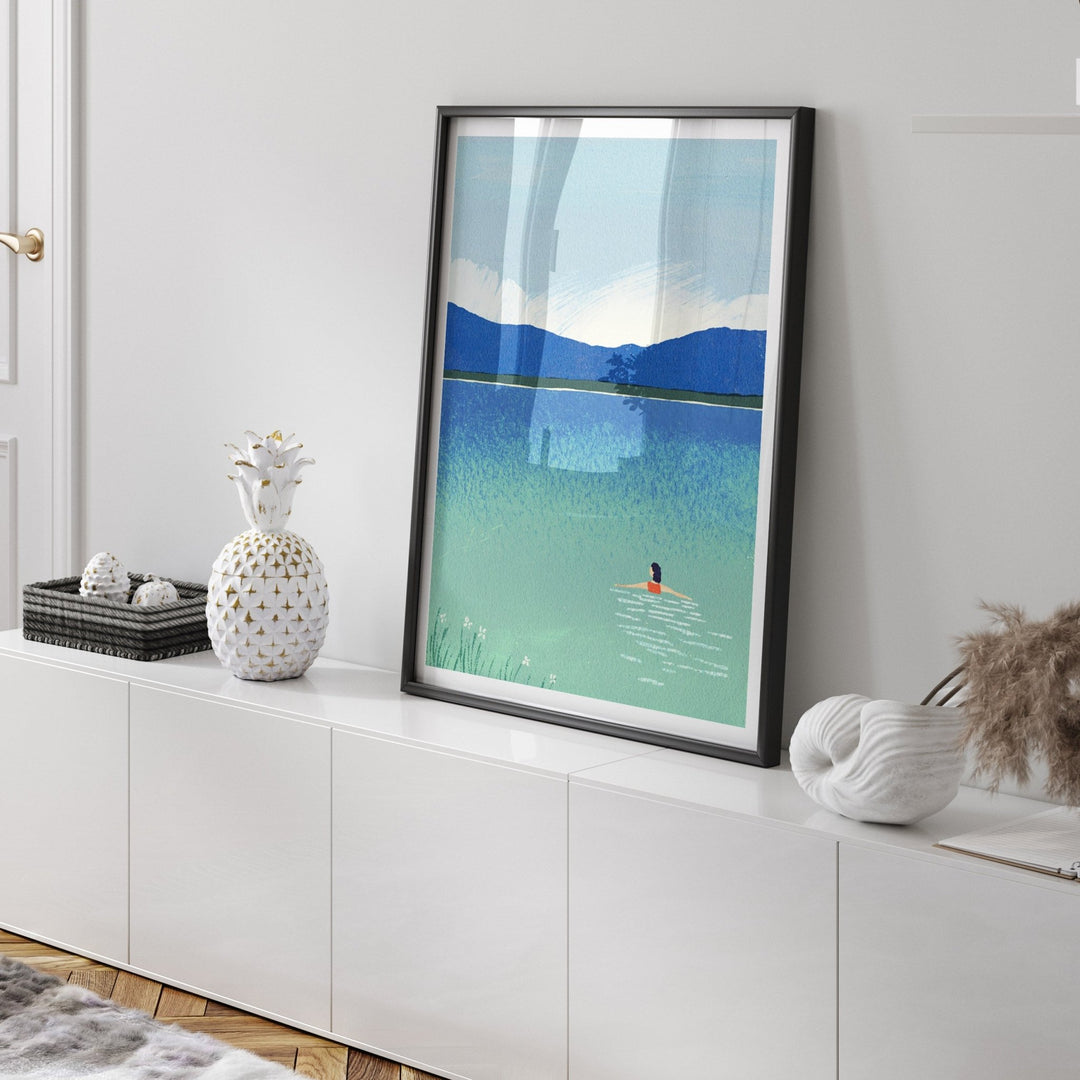 Artwork of a person swimming in a lake with mountains on a white wall.
