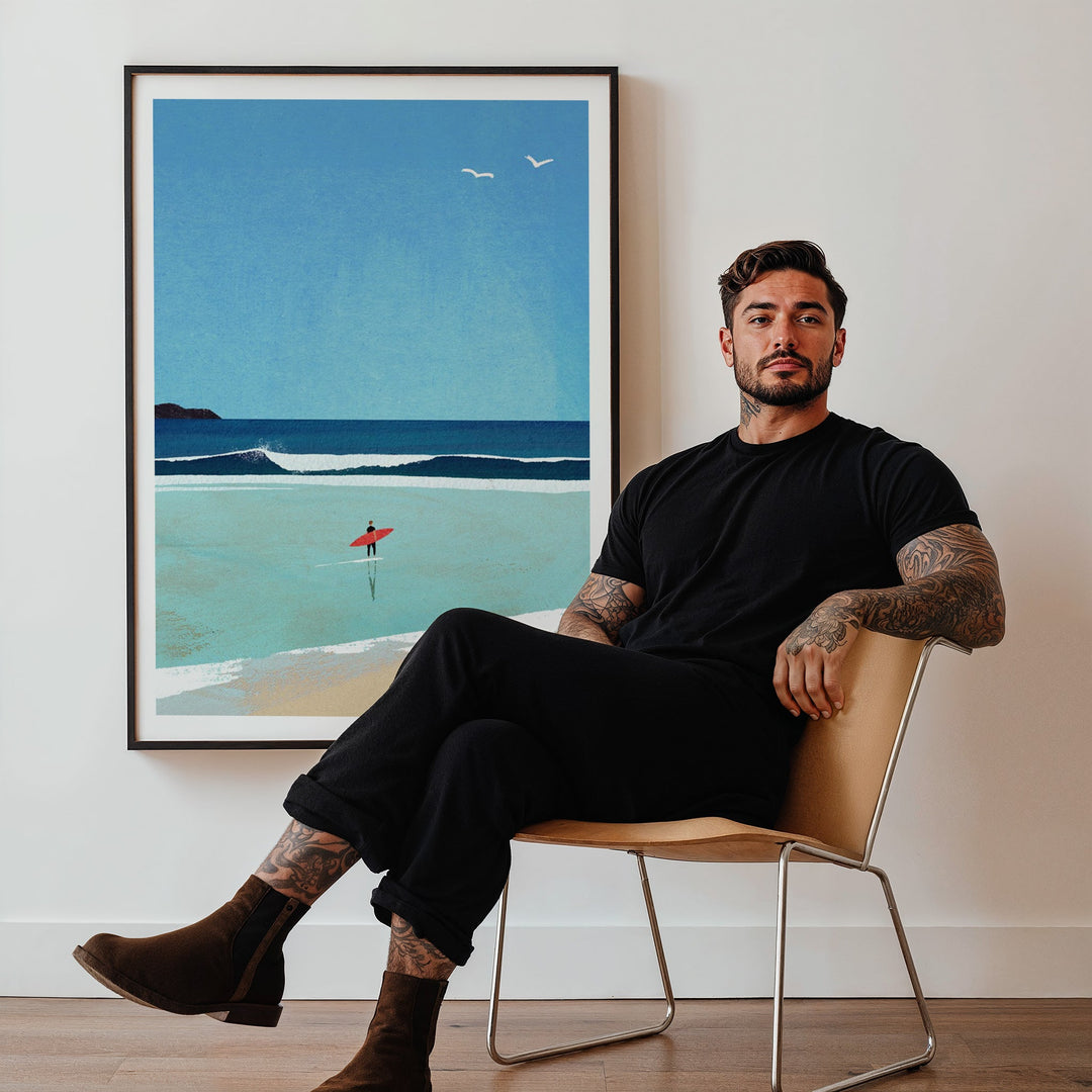 Man sitting on a chair in a room with artwork of a beach scene.