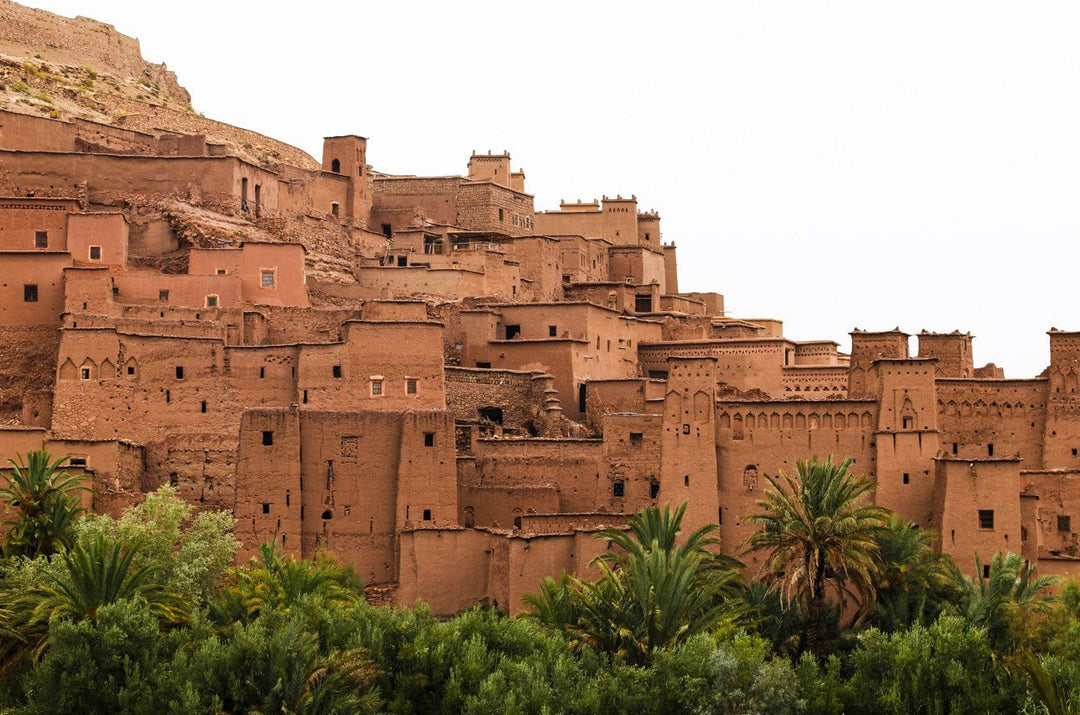Traditional Moroccan kasbah with palm trees in the foreground framed