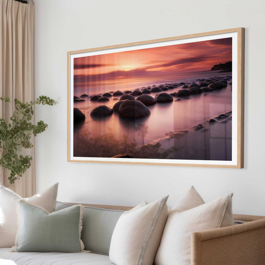 Modern living room with wicker furniture, a sofa, and an artwork of a sunset over water.