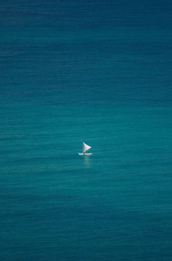 Sailboat in the middle of a vast blue ocean framed