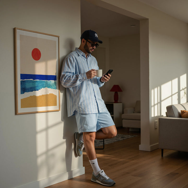 guy leaning against wall holding cup