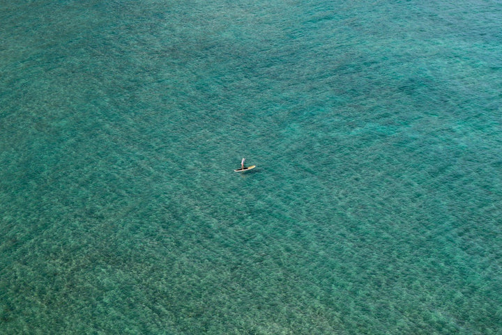 Person swimming in a vast expanse of clear blue water framed