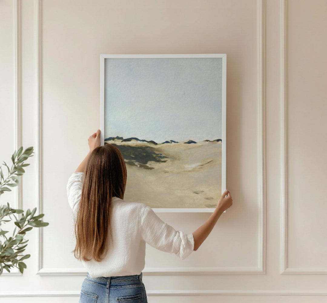 Woman hanging a landscape painting on a wall