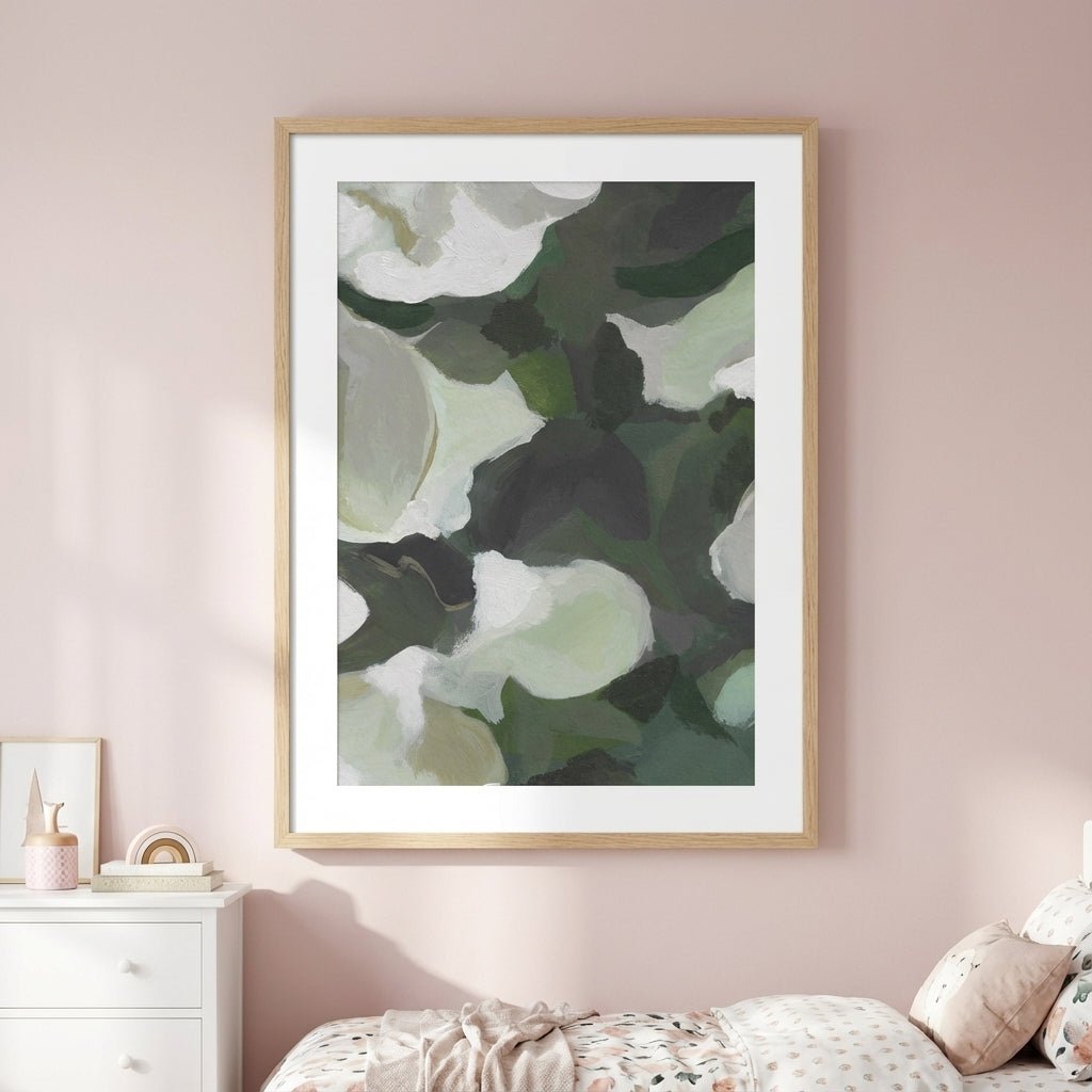 Abstract art print of green and white flowers on a pink wall.