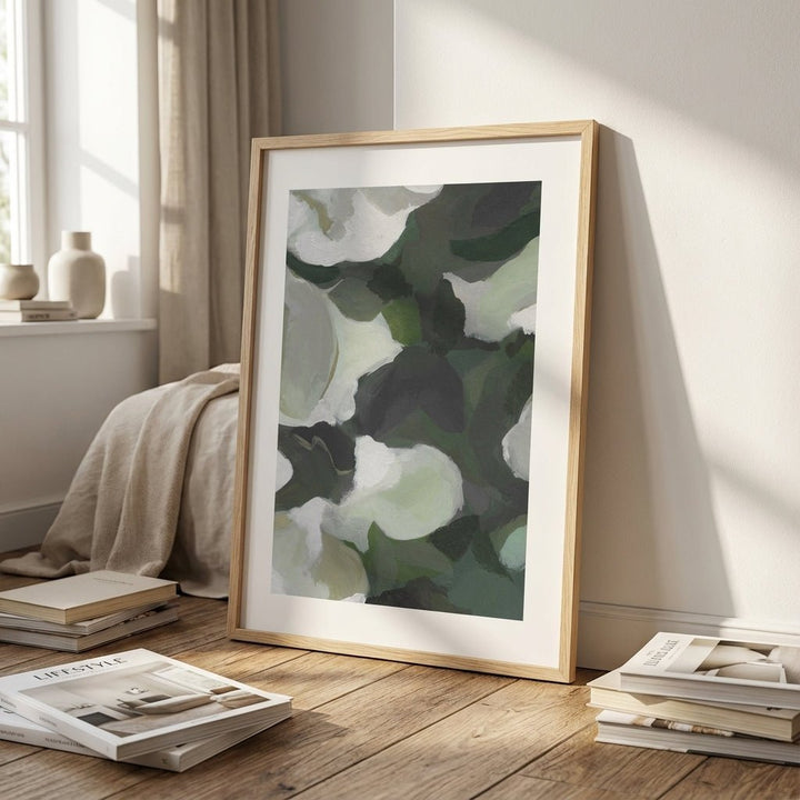 Abstract art print on a wooden floor with books and a blanket.