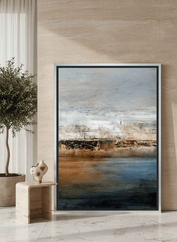 Oversized statement canvas wall art with a silver leaf surround leaning against the wall in a luxe living room