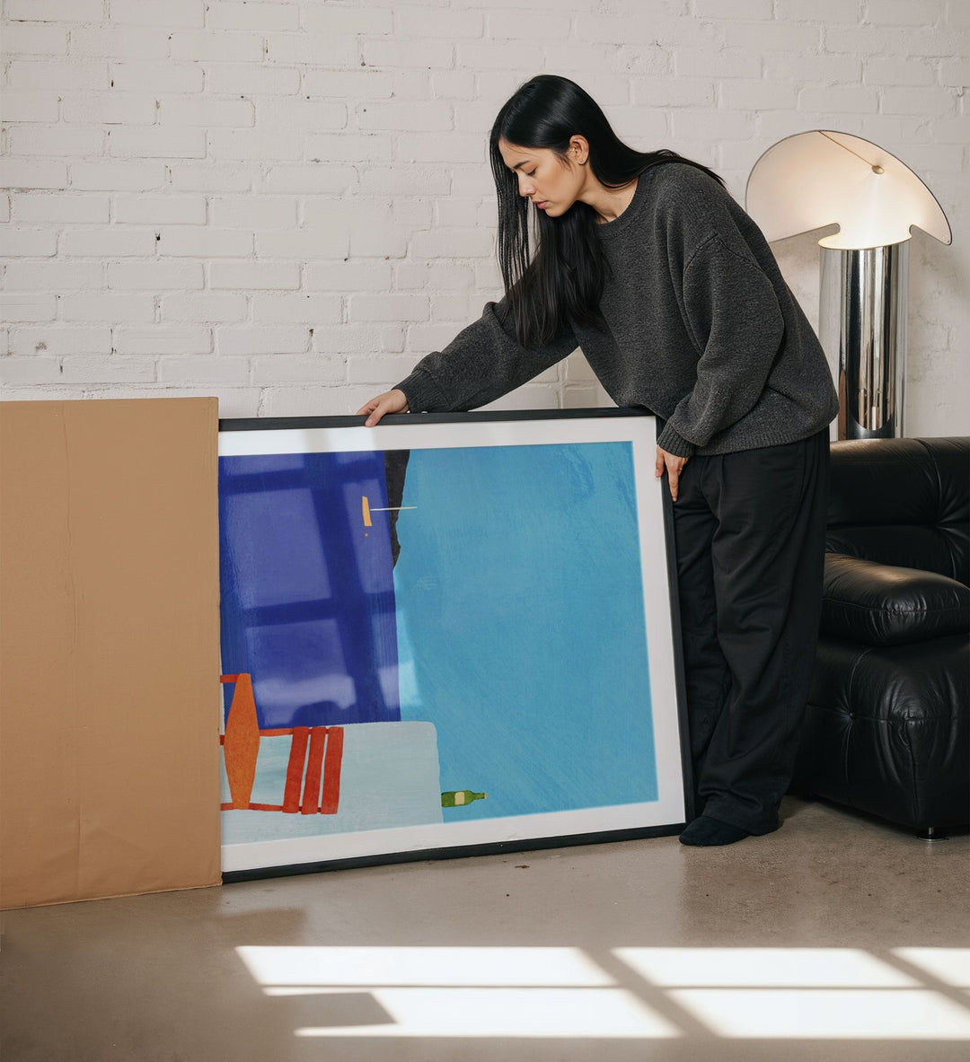 Woman holding abstract painting in a living room.