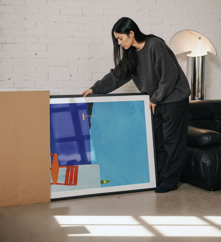 Woman holding abstract painting in a living room.