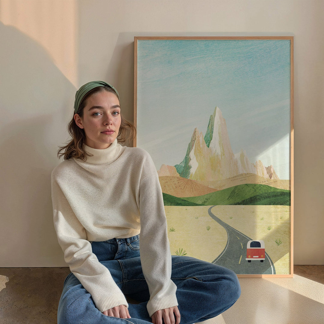 Woman sitting on the floor in front of a painting of a landscape with a road and van.