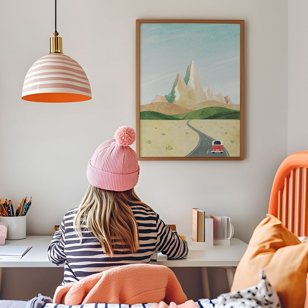 Person wearing a pink beanie sitting at a desk with a colorful painting on the wall.