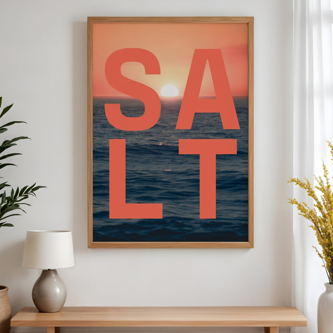 Artwork with 'SALT' text and sunset over water design, placed above a wooden bench in a room.