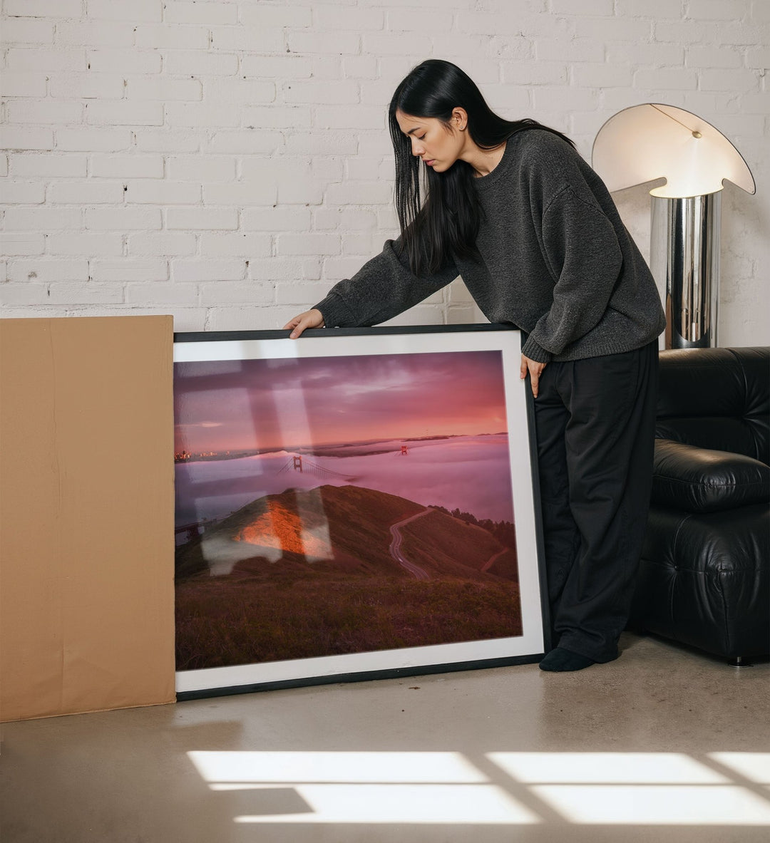 Woman holding a large artwork in a living room.